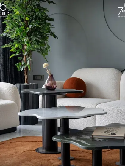 The living area in 'The House of Arcs' features unique, petal-shaped nesting coffee tables in different marbles. These custom pieces add an organic and artistic touch to the room.