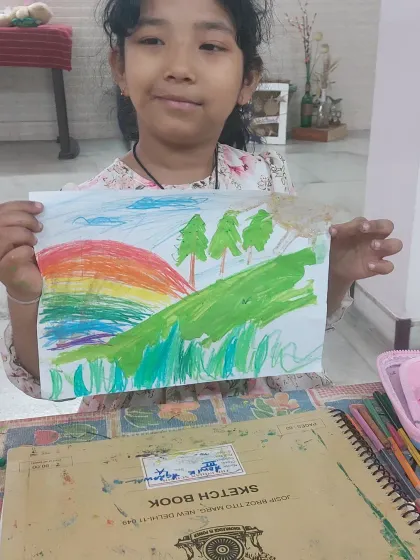 A beautiful landscape drawing with a rainbow, trees, and grass. This piece showcases the child's ability to combine different elements to create a complete scene.