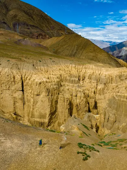 The surreal, eroded landscape of Lamayuru, often called the "Moonland" of Ladakh. The scale is hard to comprehend until you see the tiny figure of a person standing amidst the formations.
