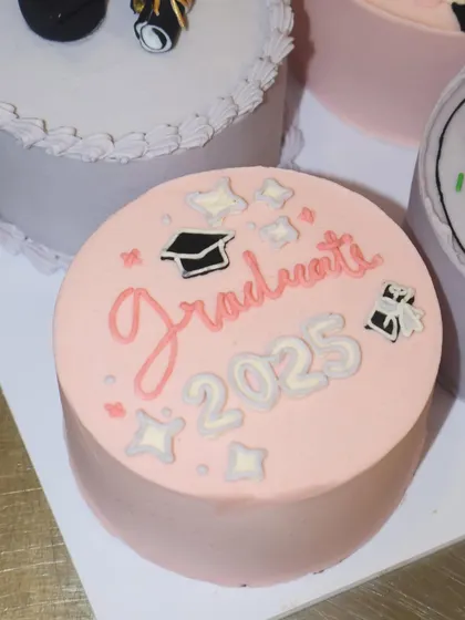 A pretty-in-pink graduation bento cake for the class of 2025. The hand-lettered "Graduate" message and sparkling star details add a touch of magic to this celebratory mini cake.