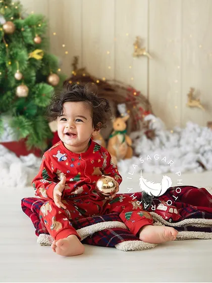A festive Christmas-themed milestone session. This little one is enjoying the holiday props, with a big smile on his face.