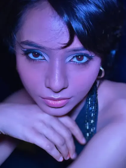 The same airbrush look under cool, blue lighting, showing how the makeup transforms and stands out in a party environment.