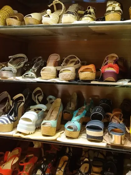 A beautiful collection of wedges and heels, neatly organized on glass shelves. Storing them this way protects the shoes and makes it easy to choose a pair.