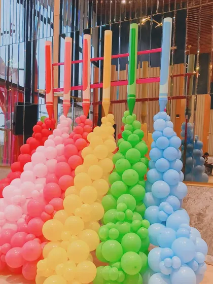 A unique crayon-themed balloon sculpture. Each color flows from a giant crayon prop, creating a vibrant and imaginative entrance piece for an art-themed party.