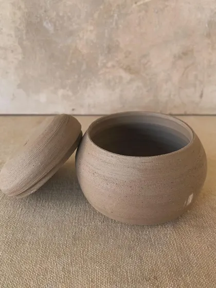 A raw, unglazed lidded jar, showing the clean lines and smooth finish of the wheel-thrown form. This piece is all about minimalist beauty.