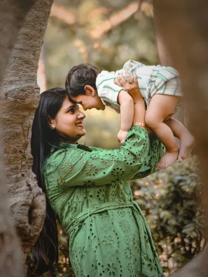 A mother's love captured in an outdoor setting. This beautiful shot of a mom lifting her son into the air is full of joy and tenderness.