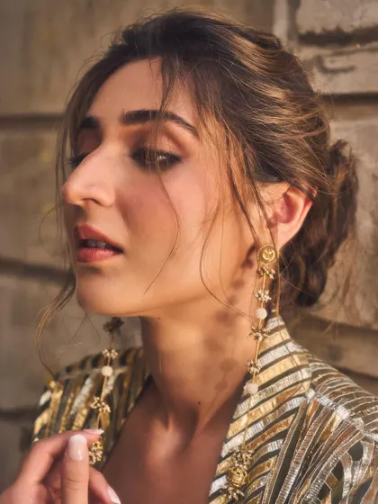 A soft and ethereal close-up. The messy bun and delicate earrings add a touch of romance to this otherwise bold and modern metallic outfit.