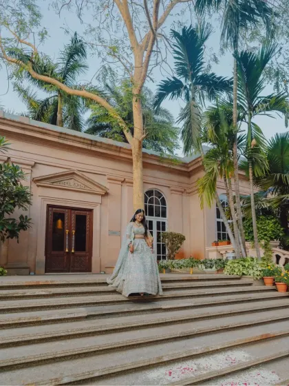 A wide shot of the bride on the steps of a beautiful venue, surrounded by palm trees.