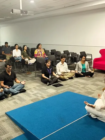 Leading a guided meditation for a corporate group, with some participants on mats and others in chairs for accessibility.