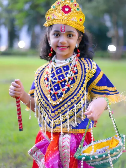 A happy and bright portrait of little Krishna, holding a basket and smiling sweetly.