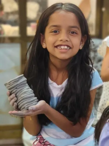 A young girl proudly holds up the vase she made using the coil-building technique. Our kids' classes teach fundamental hand-building skills in a fun and accessible way.