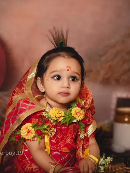 A beautiful close-up portrait of a little girl dressed as Radha, with a peacock feather in her hair.
