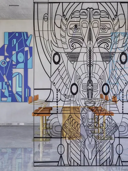 This intricate metal screen serves as a partition, dividing a space while maintaining a sense of openness. The detailed, linear design is inspired by ancient art forms, reimagined to create a modern totem that separates and connects simultaneously.