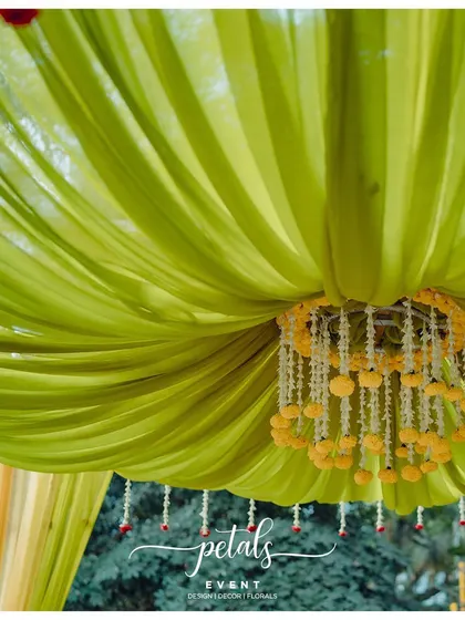 A close-up of the small floral chandelier and apple base fabric decor. These details add a touch of whimsy and elegance to the overall design of the wedding mandap.
