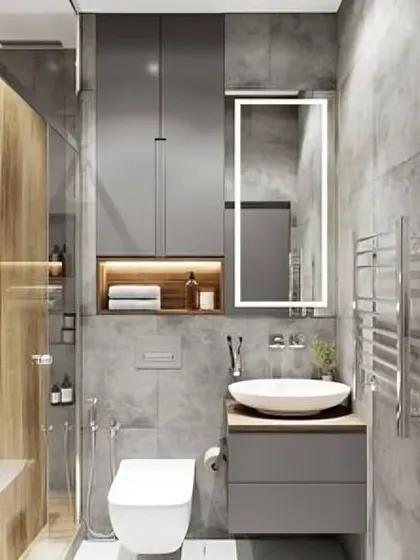 This compact bathroom design features grey cabinets, a vessel sink, and a back-lit mirror. The glass shower partition keeps the space feeling open.