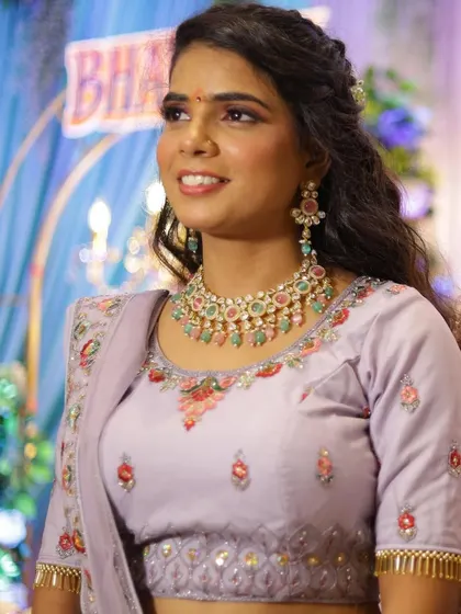 This bride chose a stunning lavender lehenga for her engagement. The makeup features complementary pink and lavender tones on the eyes and a natural base, paired with wavy curls.