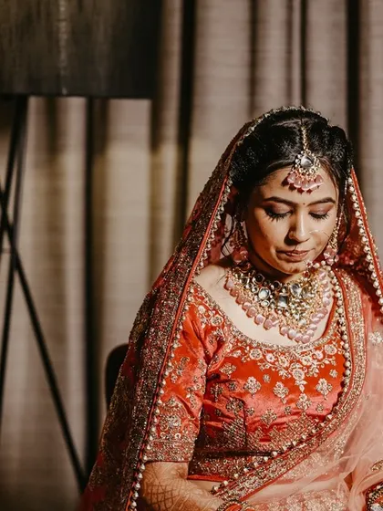 A quiet, pensive portrait of the bride in her beautiful red and pink lehenga before the ceremony.