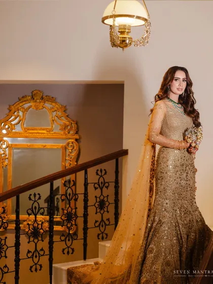 A bride descending the grand staircase. This shot captures the elegance and drama of the moment, with the golden mirror adding to the regal atmosphere.