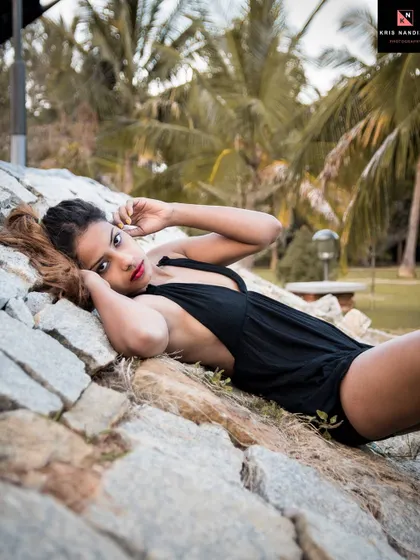A 'Boho' themed outdoor shoot. The model lies on a bed of rocks in a black halter dress, her pose and the natural setting creating a free-spirited and earthy vibe.