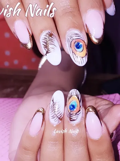 Showcasing high-level artistry, this custom nail set includes hand-painted peacock feathers with a central blue gem, paired with a modern gold-tipped French manicure.