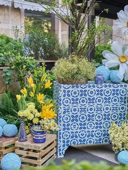 A whimsical decor corner with oversized paper daisies, sunflowers, and blue yarn balls arranged on and around rustic wooden crates.