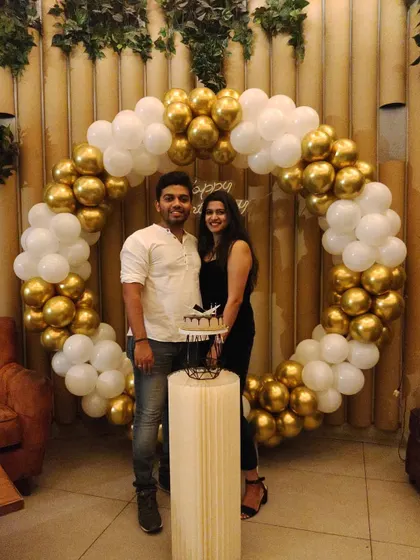 A classic gold and white balloon circle arch is a fantastic way to frame your celebration photos. Here, the couple stands proudly with their cake, marking a special birthday moment in front of the decor I set up for them.