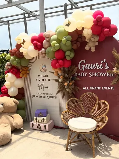 The main backdrop for the baby shower, featuring a wicker peacock chair for the mom-to-be and props like a teddy bear aviator.