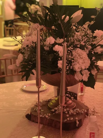 A classic and elegant centerpiece with a large bouquet of white flowers and tall, slender candles on a wooden base. This timeless look is perfect for any formal celebration.