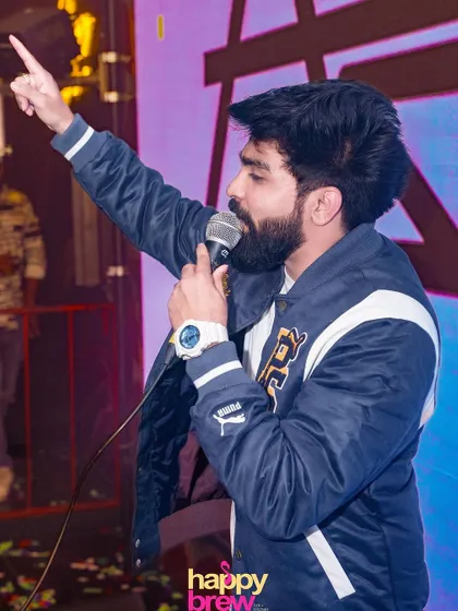 On the mic at Happy Brew, pointing to the sky and getting the crowd hyped.