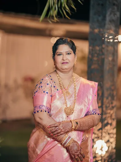 A full-length shot of the bride's mom, looking graceful in her pink silk saree. The makeup is designed to be flattering and long-lasting.