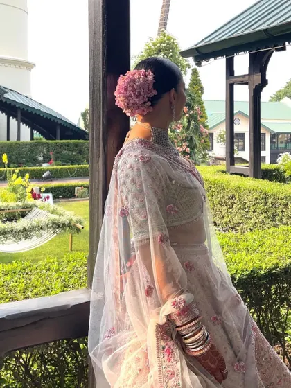 A side view of the bride looking out from a balcony. The floral bun adds an element of elegance to her profile.