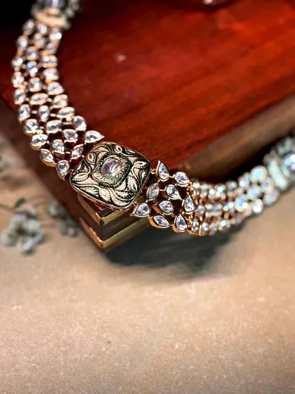 A close-up of a multi-row polki diamond necklace with a central hand-painted enamel motif.