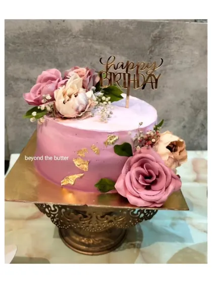 A pretty pink floral cake for a birthday. The combination of pink buttercream, gold leaf, and fresh flowers creates a beautiful and celebratory design.