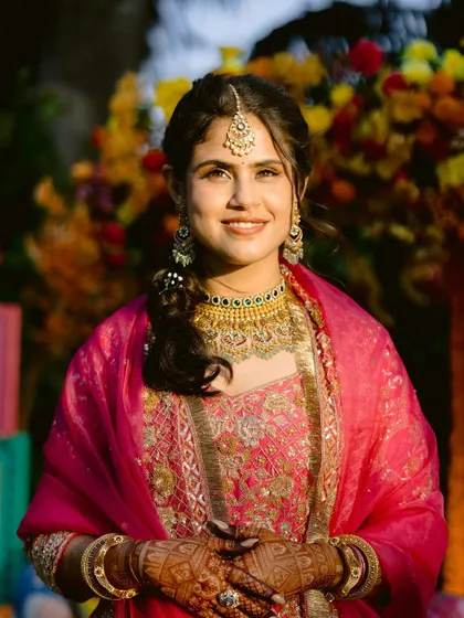Caught in the golden hour. This bride looks absolutely radiant for her pre-wedding event in a beautiful pink outfit, with makeup that enhances her natural glow.