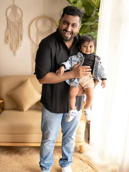 A father holds his son, who is dressed in a cool denim jacket. Their matching expressions of happiness make this a fun and memorable father-son portrait.