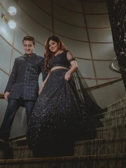 The couple descending a grand staircase, looking elegant and ready for their party.