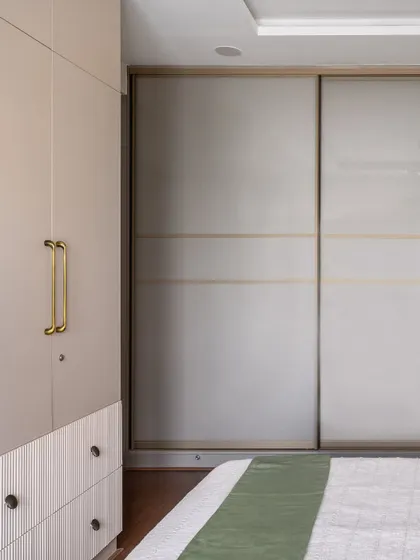 The sliding wardrobe in the master bedroom has a subtle, elegant design with thin brass lines, complementing the other metallic accents in the room.