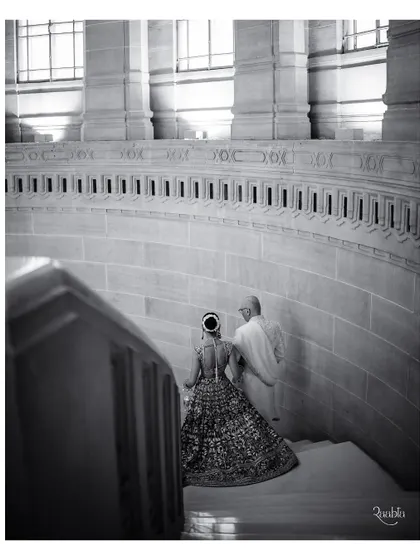A timeless black and white shot of the bride descending the grand stone staircase of the palace, her lehenga trailing behind her.