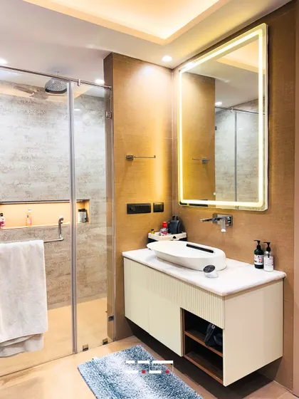 A clean and contemporary bathroom with a floating vanity, a vessel sink, and a large backlit mirror. The walk-in shower with a glass partition makes the space feel open and bright.
