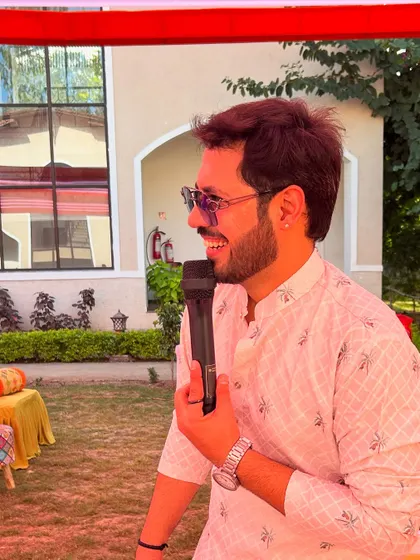 A side profile with a mic, captured during a candid moment of laughter while hosting an outdoor Haldi.