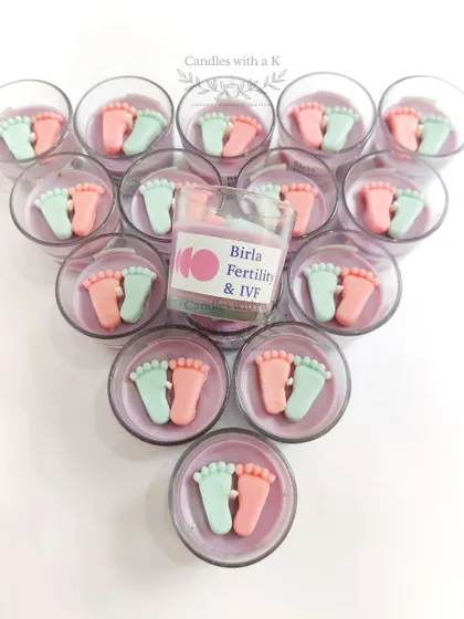 A top-down view of the baby feet candles, arranged in a triangle, showcasing the custom logo sticker for the corporate order.
