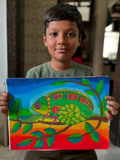 A young student proudly holds up his finished chameleon drawing. It's wonderful to see the satisfaction on their faces when they complete a piece they've worked hard on.