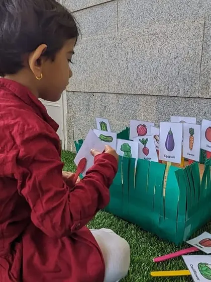 A young girl matches vegetable cards to their correct spots in our pretend garden. Hands-on games like this make learning about nature and food sources engaging.