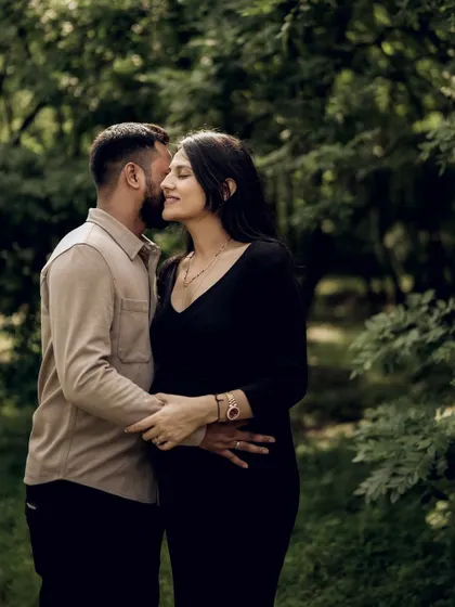 A tender moment captured in the woods. He whispers in her ear as they embrace, a private and romantic gesture.