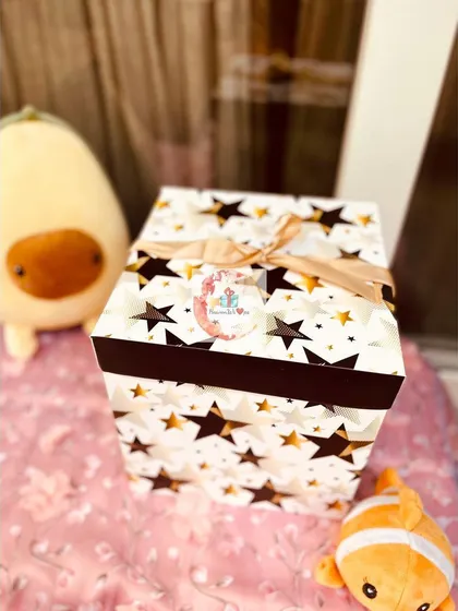 The exterior of our kids' gift hamper, a tall box decorated with a fun star pattern and tied with a ribbon.
