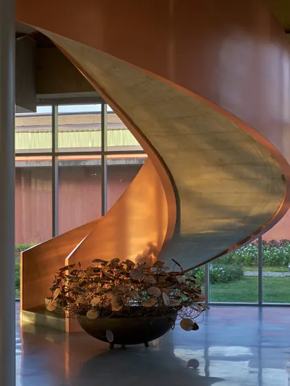 A sculptural, copper-toned staircase that appears to float in the space. This is an example of how we treat functional elements like staircases as opportunities for artistic expression and geometric exploration.
