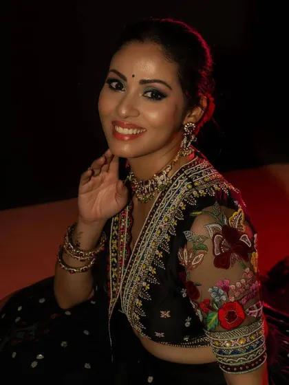The blouse for this black lehenga features sheer sleeves with colorful floral embroidery, continuing the theme from the skirt. This detail adds a touch of delicacy to the bold and dramatic ensemble.