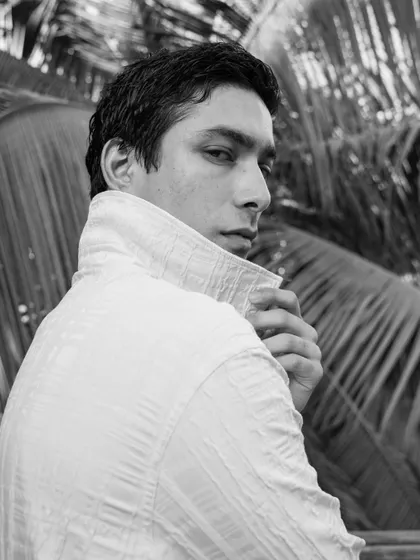 A strong, over-the-shoulder pose against a natural backdrop. This classic male model pose highlights the jawline and creates a confident look.
