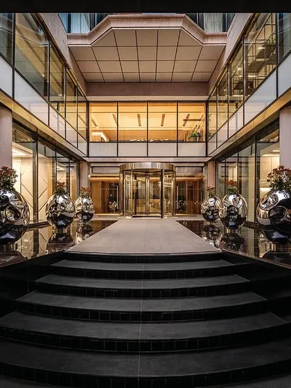 A symmetrical view of the entrance steps and open-air courtyard, flanked by large, polished steel planters that add a modern touch to the classic architecture.