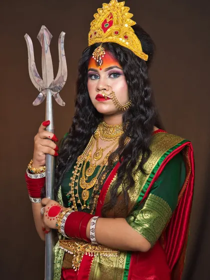 Holding a trishul, this student's portrayal of Maa Durga is powerful and detailed. The makeup includes a third eye and traditional Bengali elements, taught in our character makeup modules.